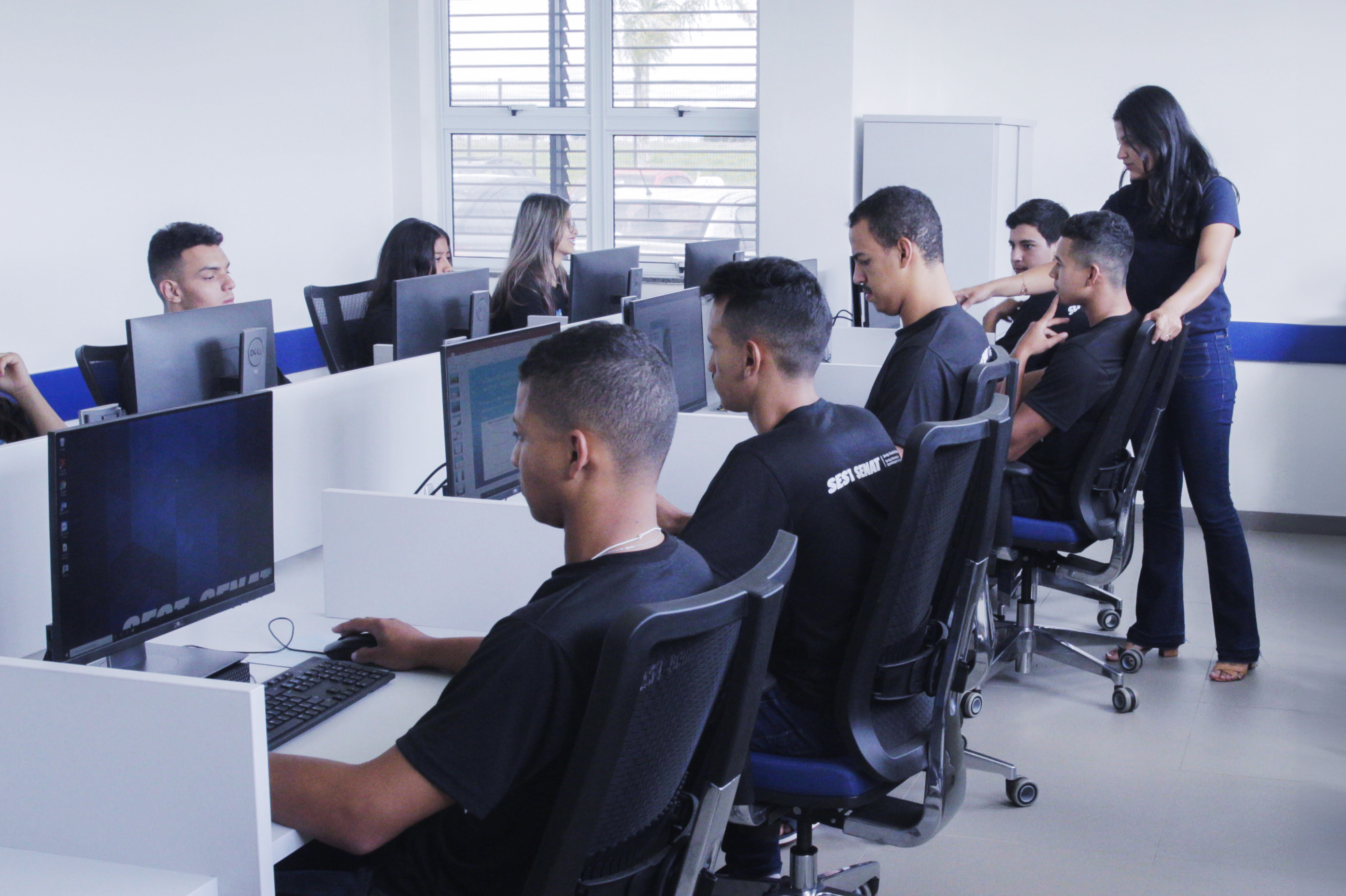 Grupo de alunos do EaD SEST SENAT em um laboratório de informática utilizando computadores